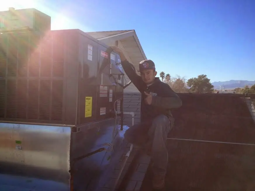 HVAC technician performing AC Tune-Up on a rooftop unit in Olney
